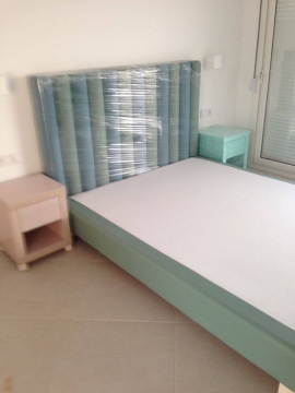 Κρεβάτι ντυμένο και κομοδίνα σε χρωματιστή λάκα σε ξενοδοχείο της Χαλκιδικής